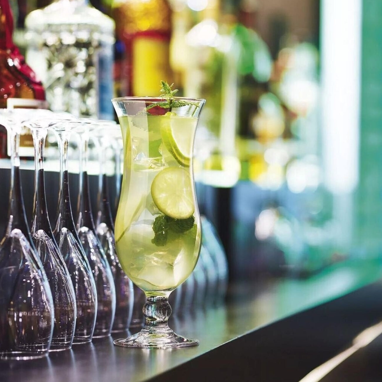 Cocktail serveret i Arcoroc Hurricane glas på bar med lime og mynte – professionelt cocktailglas i brug
